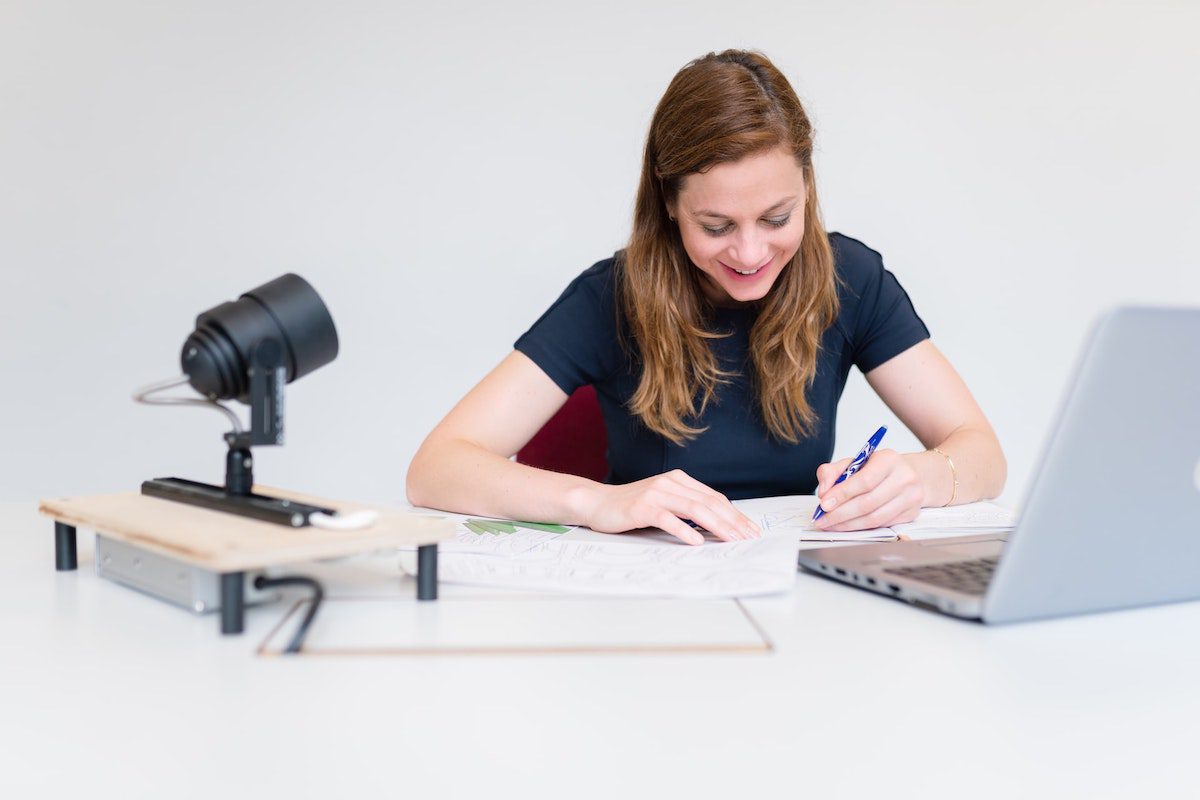 Woman smiling while taking notes from her full stack bootcamp prep course in front of an open laptop.
