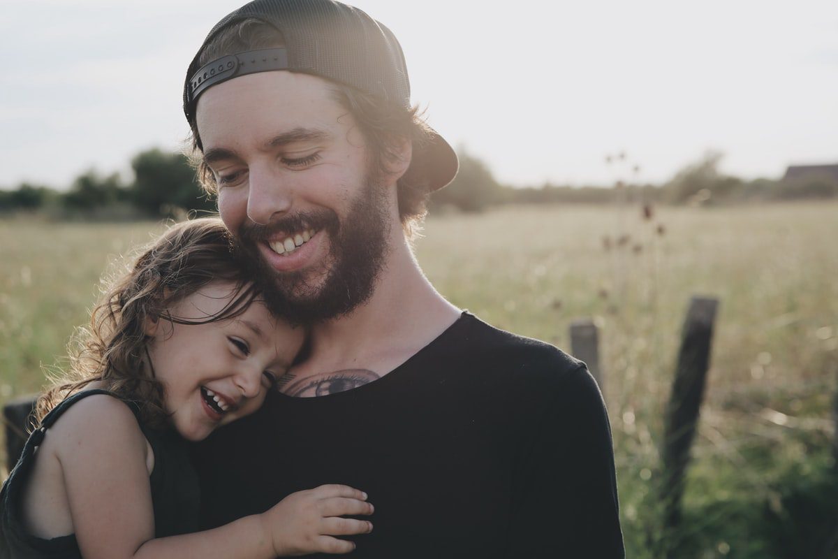 A single father hugs his daughter while both smile and laugh