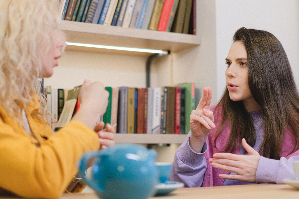 Two students sitting at a table having a conversation in sign language
