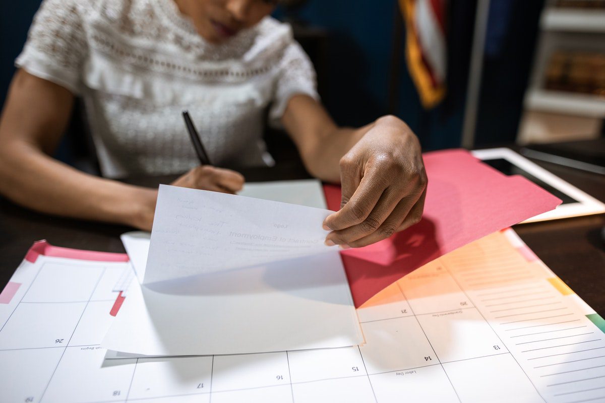 Woman writing on a piece of paper placed on top of a calendar