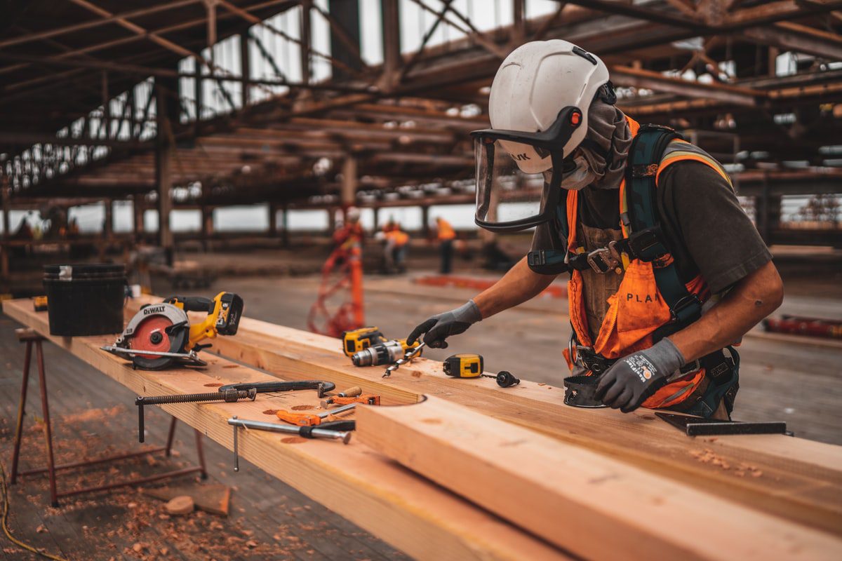 A construction worker measures and cuts plywood on a construction site