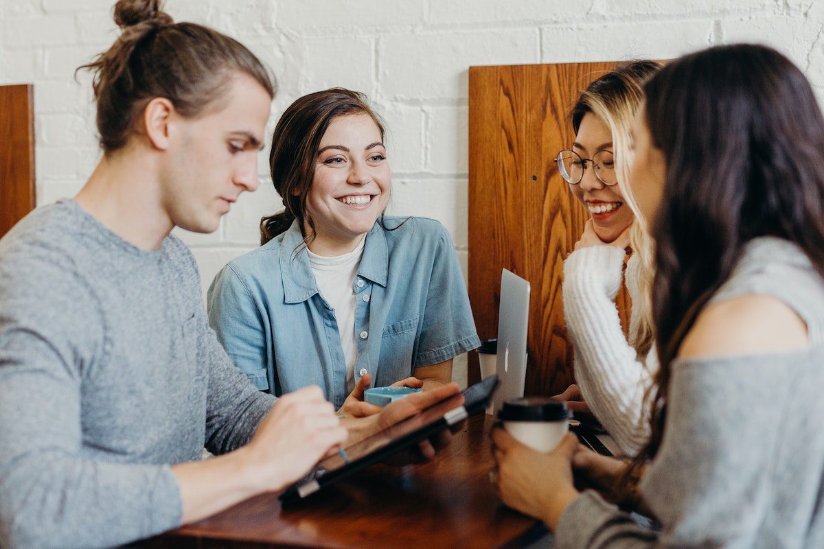 Four happy students receiving a high level of education by attending an in-person coding bootcamp. How Much Does Coding Bootcamp Cost?