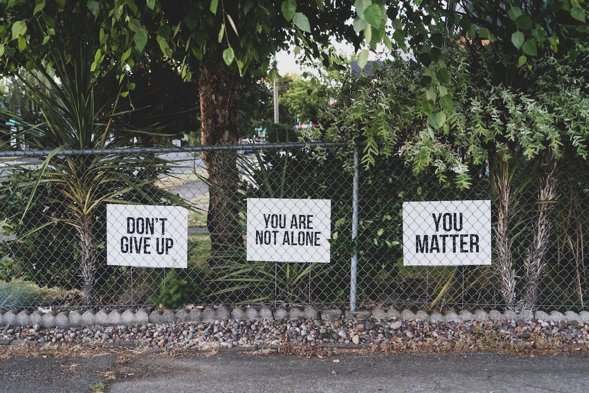 Chain-link fence with signs that say, “DON’T GIVE UP,” “YOU ARE NOT ALONE,” and “YOU MATTER.” Financial Aid For Recovering Addicts