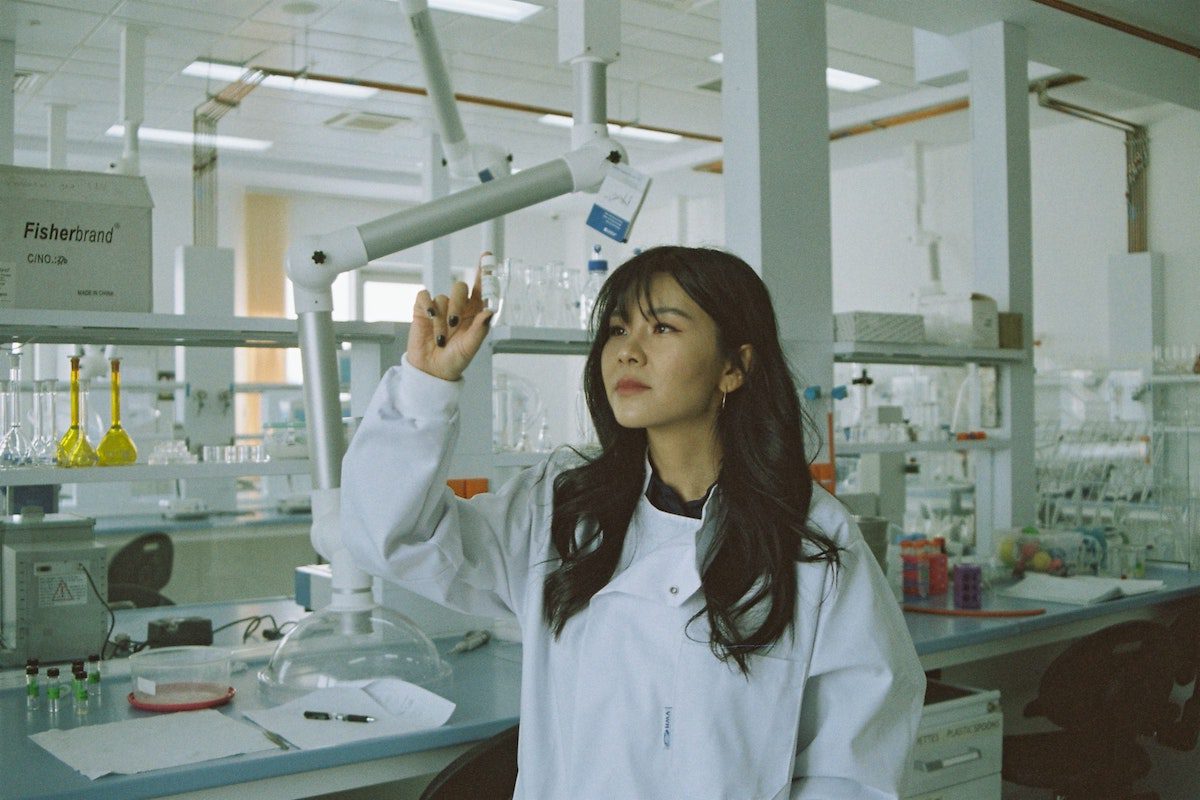 A principal scientist in a laboratory holding a beaker and working on a biotech project.
