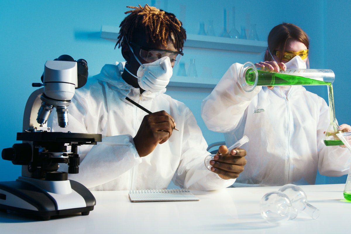 A man and a woman in lab coats doing an experiment with test tubes.