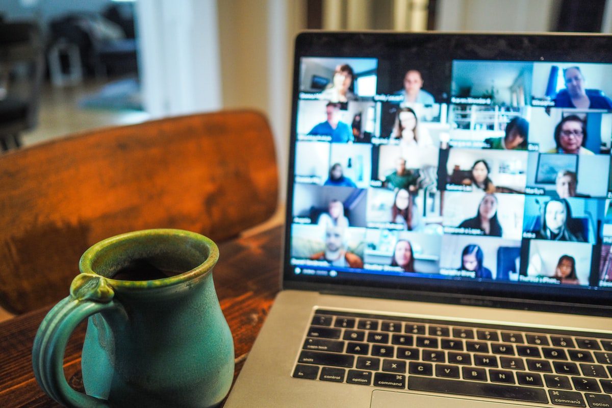 Green mug next to open laptop showing an online meeting