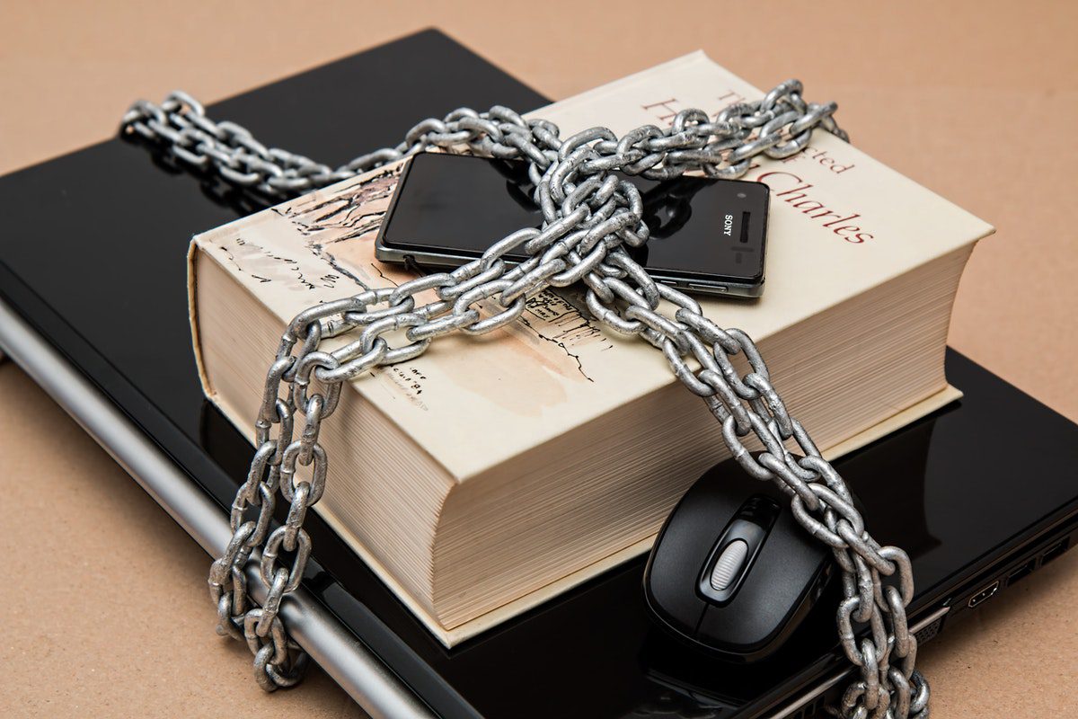 A chained laptop, book, phone, and mouse.
