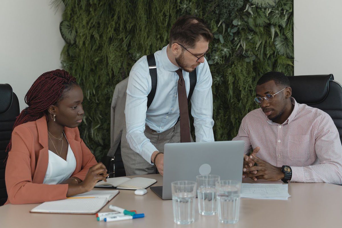 Three coworkers at a table, looking at a laptop. Highest-Paying Jobs in Colorado