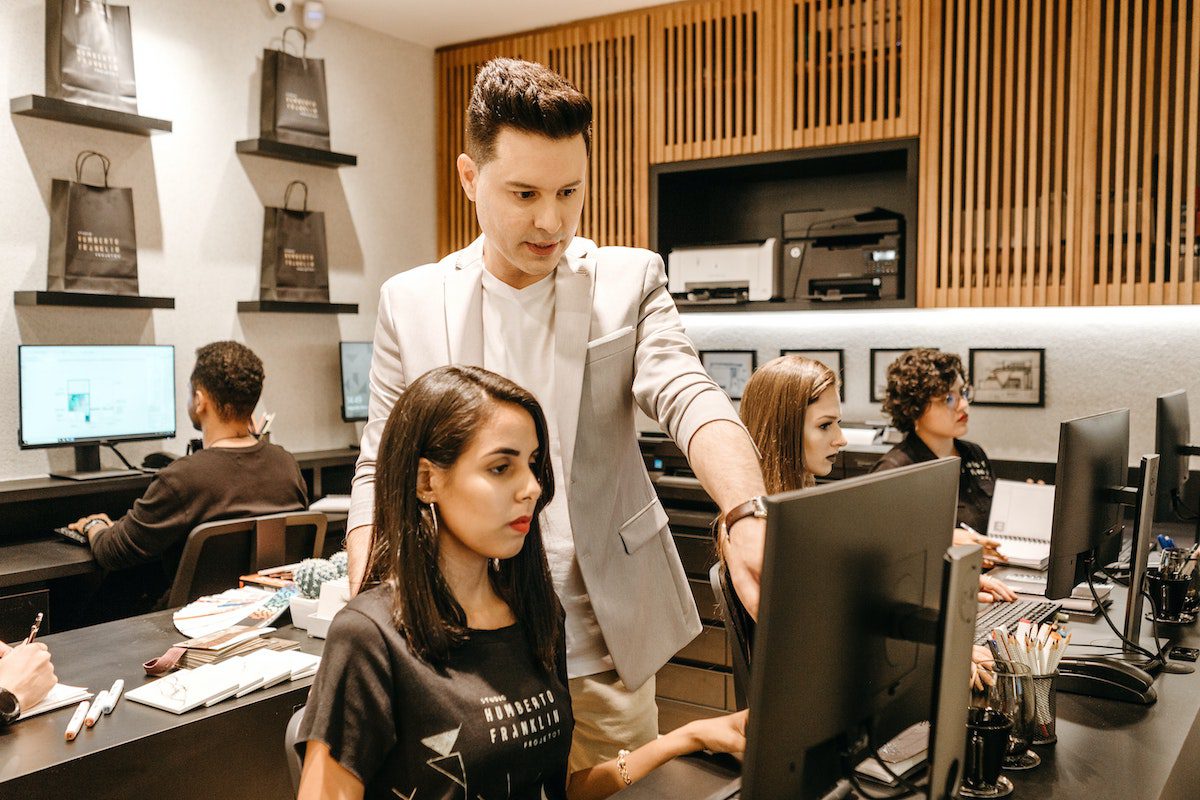 Man teaching a woman to code on a laptop at a full stack developer bootcamp.