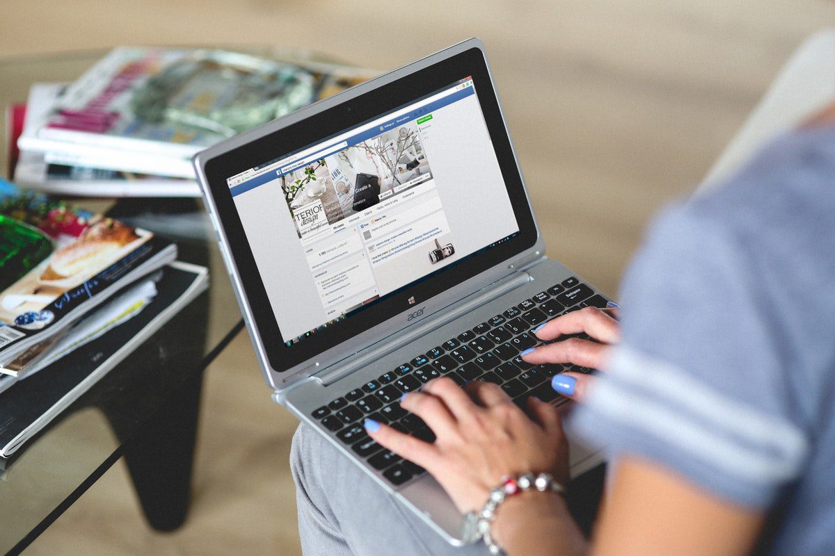 A woman uses her laptop to visit the social media platform Facebook Best Online Social Media Marketing Associate Degrees