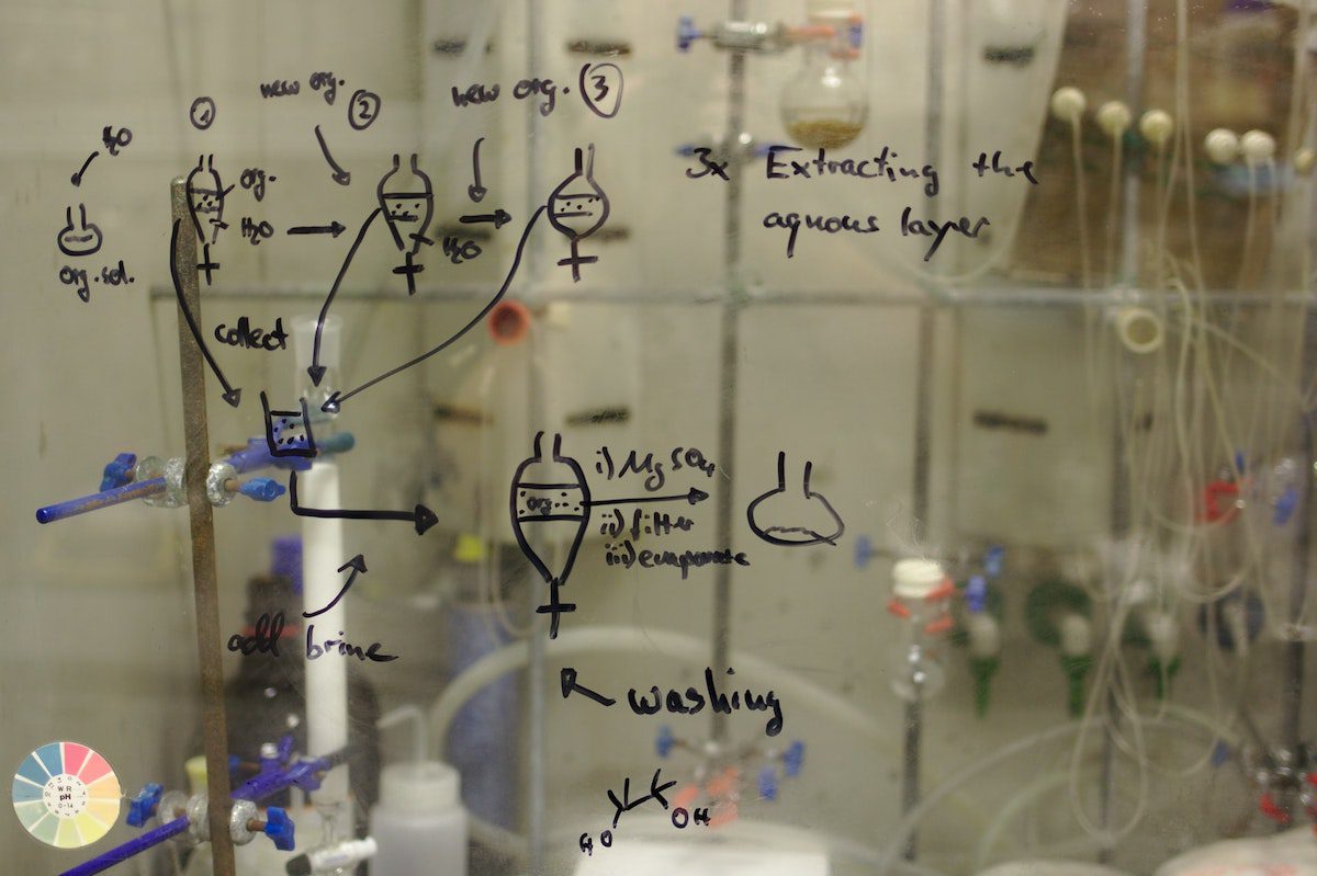 Transparent glass showing chemical equations with a titration setup behind it Best Chemical Engineering Bachelor's Degrees