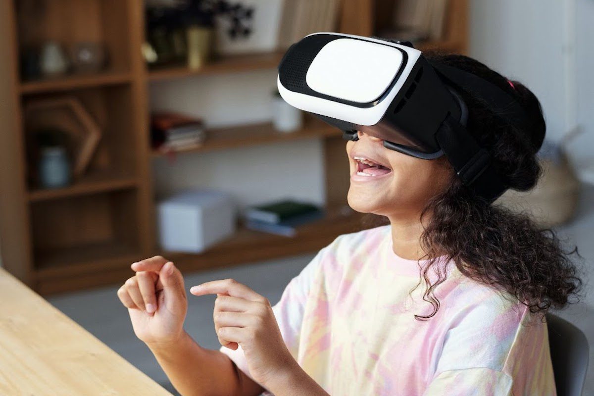 Young girl sitting at a desk wearing virtual reality headset and smiling Best Online Educational Technology Master's Degrees