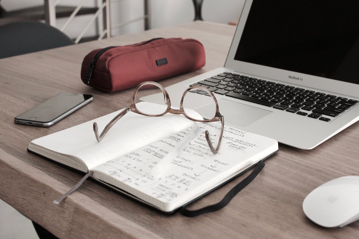 A student's study table with glasses on top of a notebook, a pencil case, a laptop, a mobile phone, and a white mouse. Best Major for Accounting