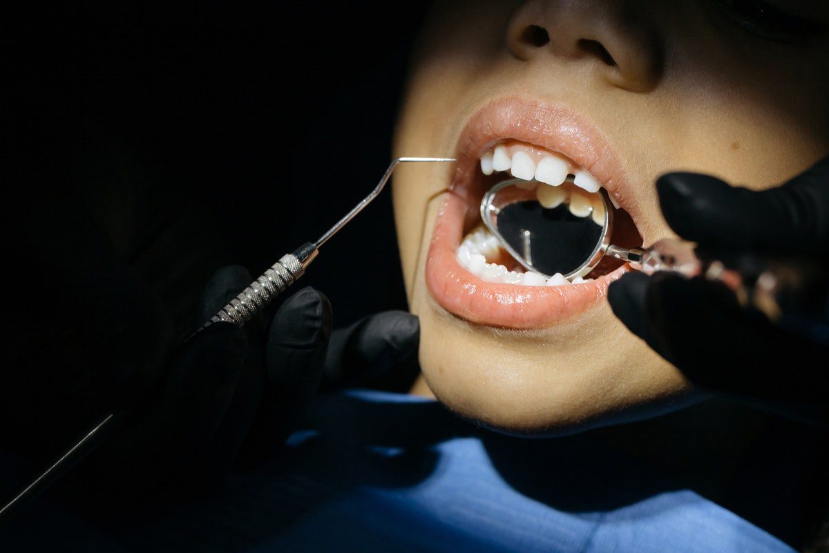 A child’s mouth is inspected with dental tools by a pediatric orthodontist