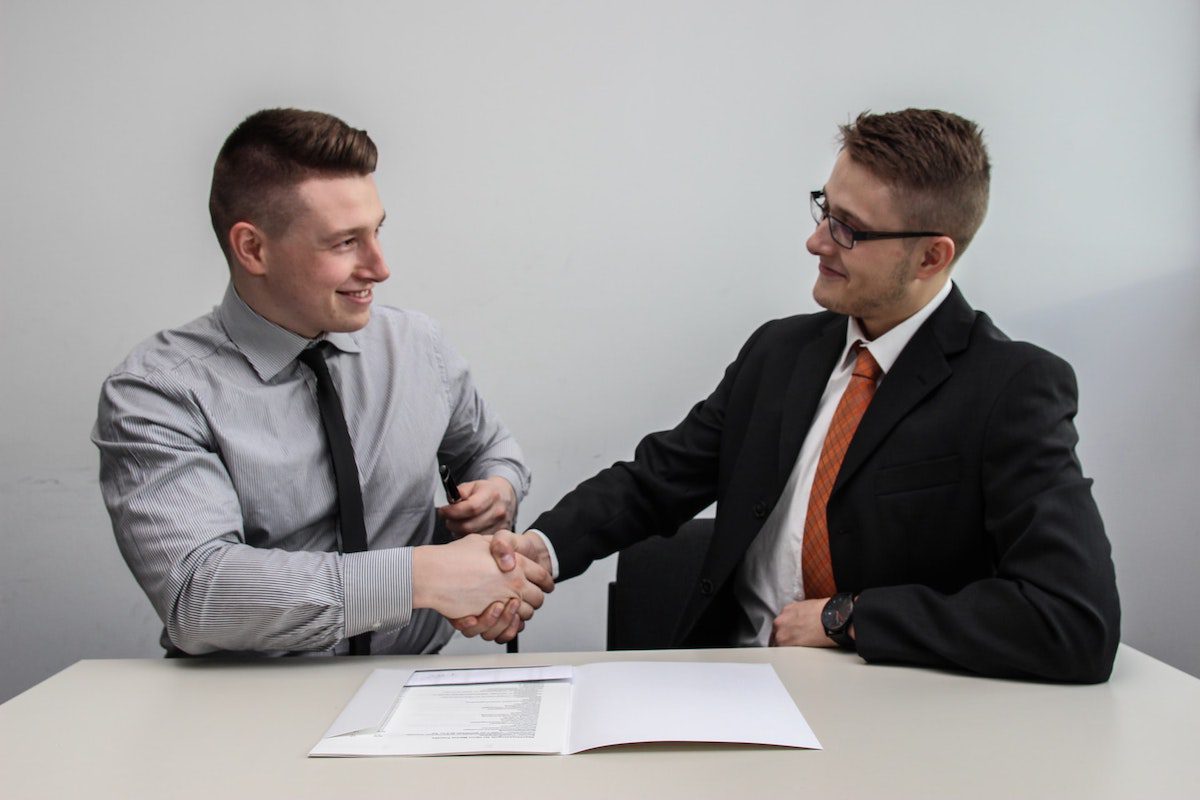 Two sales professionals shake hands after agreeing to a sale of technological products.