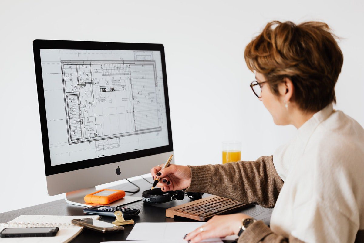 A woman looking at a blueprint of a building on a computer.