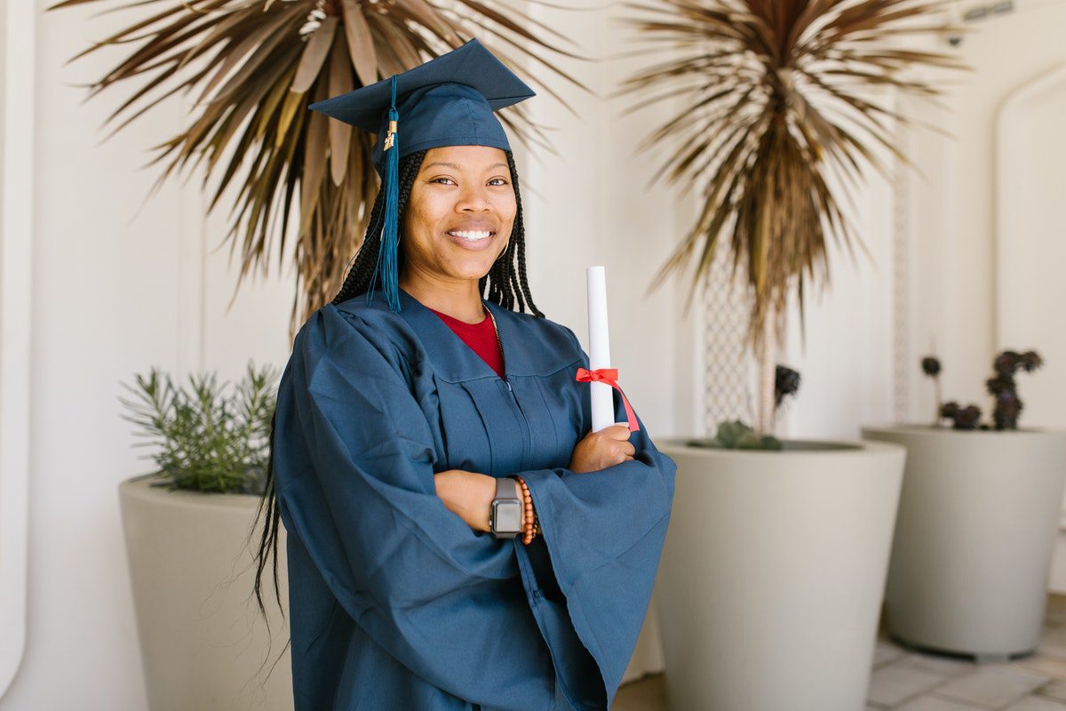 Woman standing in graduation gown and cap holding her master’s degree
