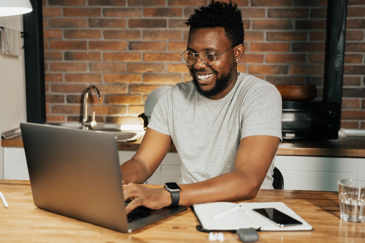 A man smiling and working from home on his laptop.