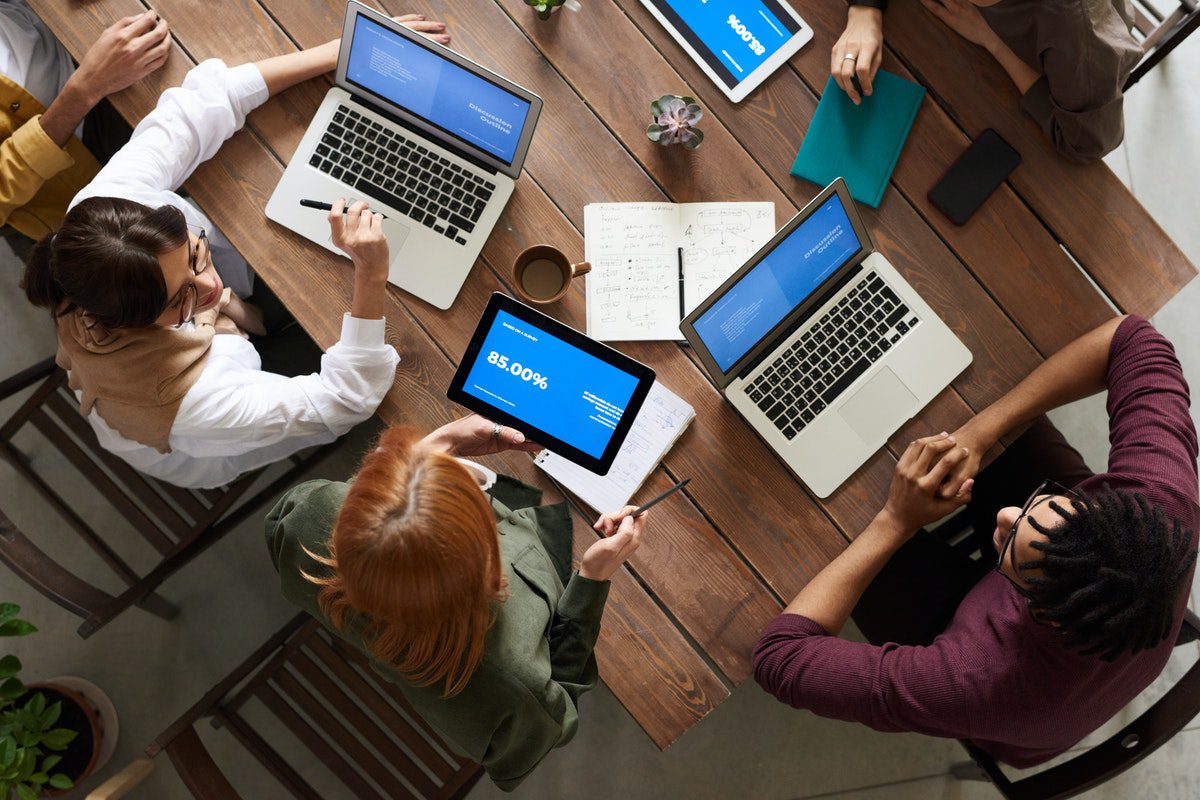 An overhead shot of five members of a software development team working on laptops and tablets