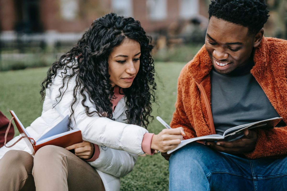 Two college students studying together on a campus lawn