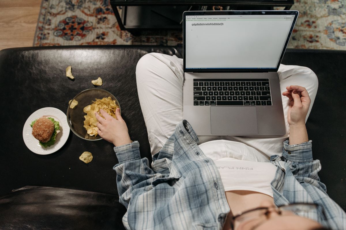 A picture of a girl eating while writing on her laptop