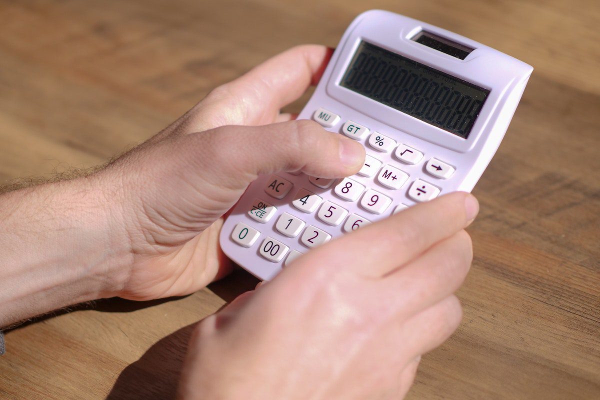 A student is holding a calculator and pressing the minus button. There are no numbers shown on the screen.