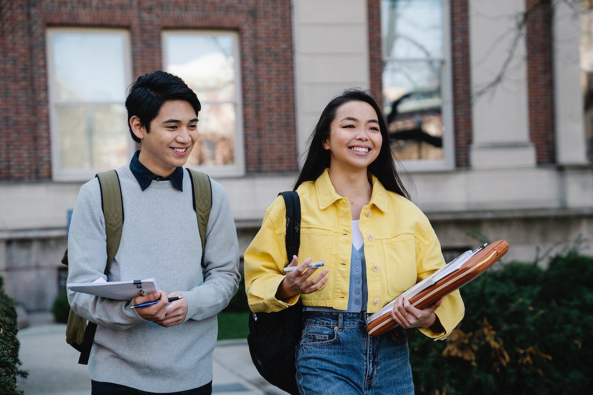 College students walking out of class holding textbooks.