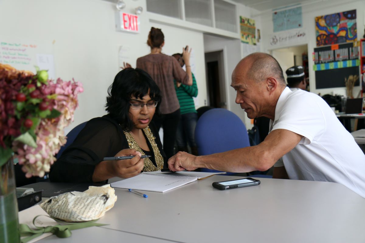 An experienced teacher helping an adult student as part of her classroom duties.