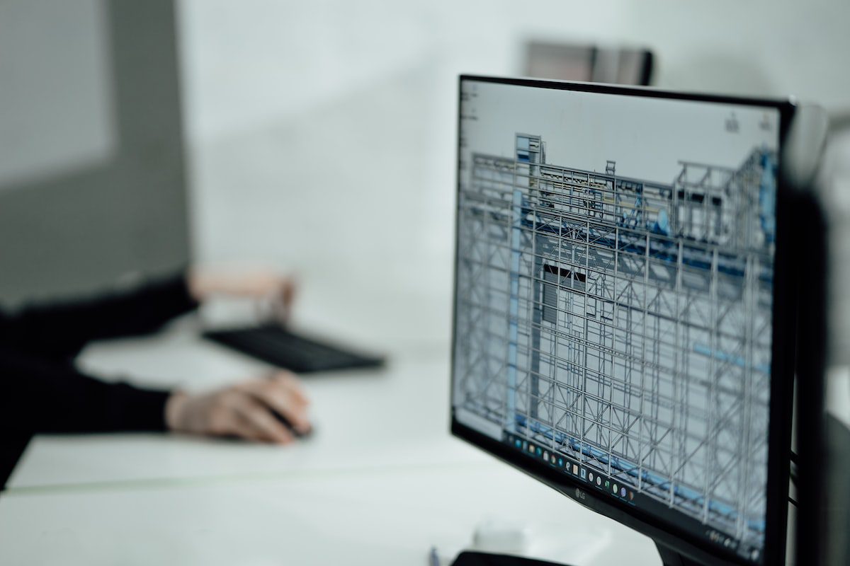 A computer monitor in an office setting displays a 3D blueprint of a building.