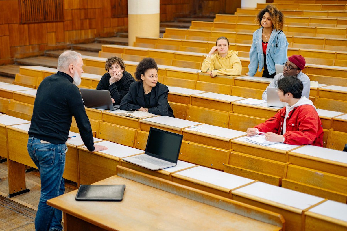 A professor teaching six students in a lecture room.