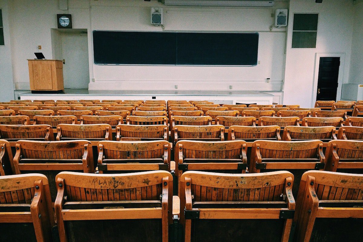 A large lecture hall with empty wooden chairs.