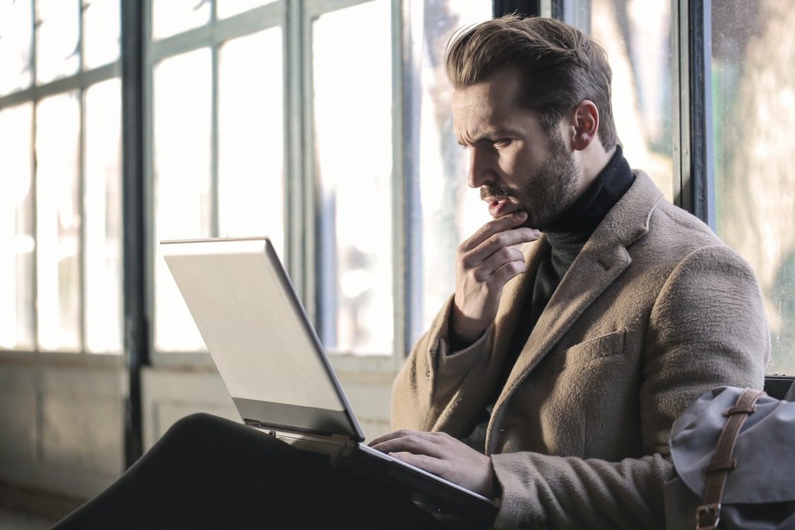 A professional thinking about how to learn to code while researching on a laptop.