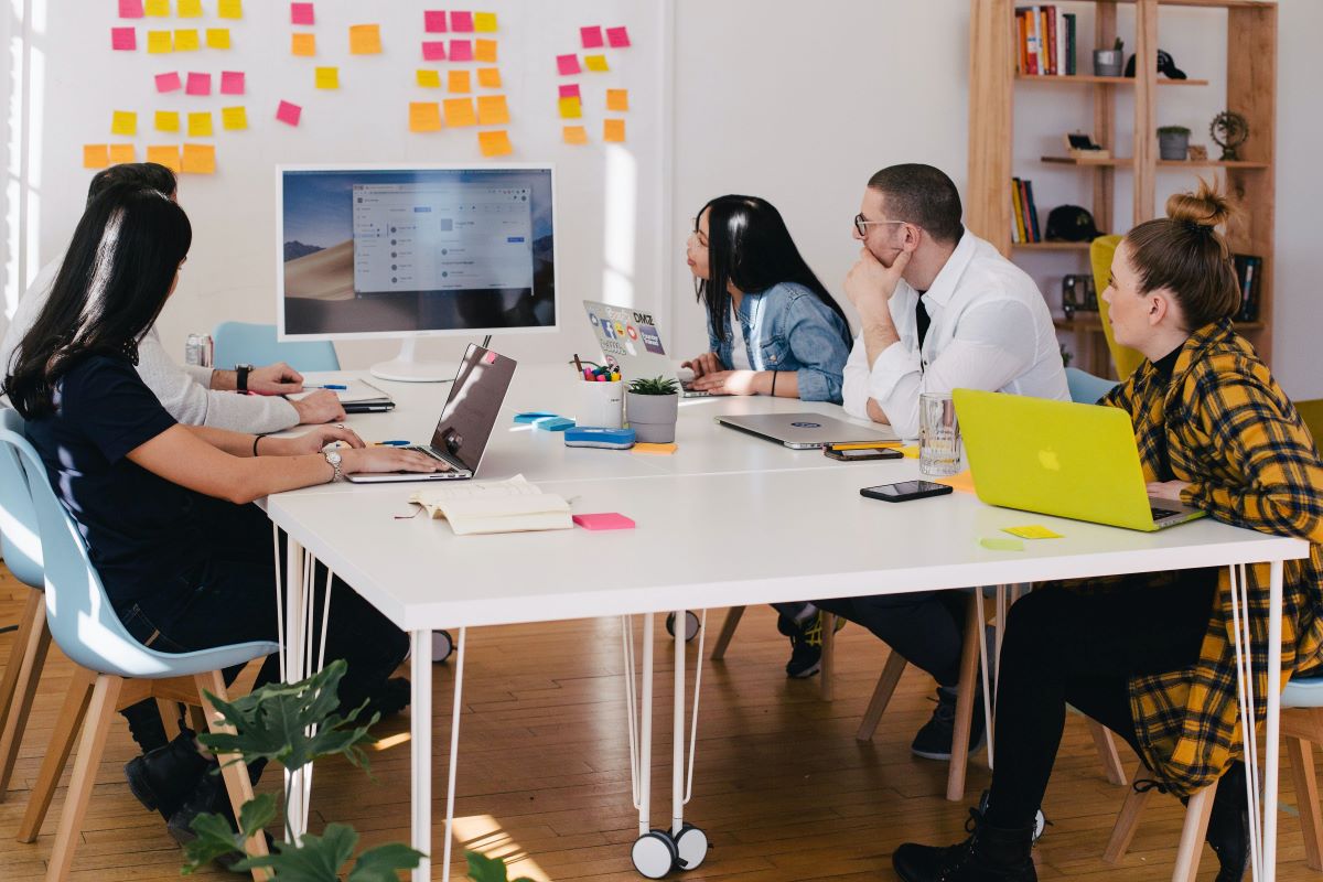 Five people in a group meeting looking at a presentation screen