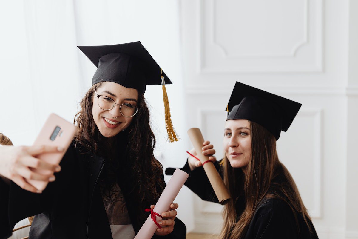 Two college graduates taking a selfie and celebrating a successful college experience. 