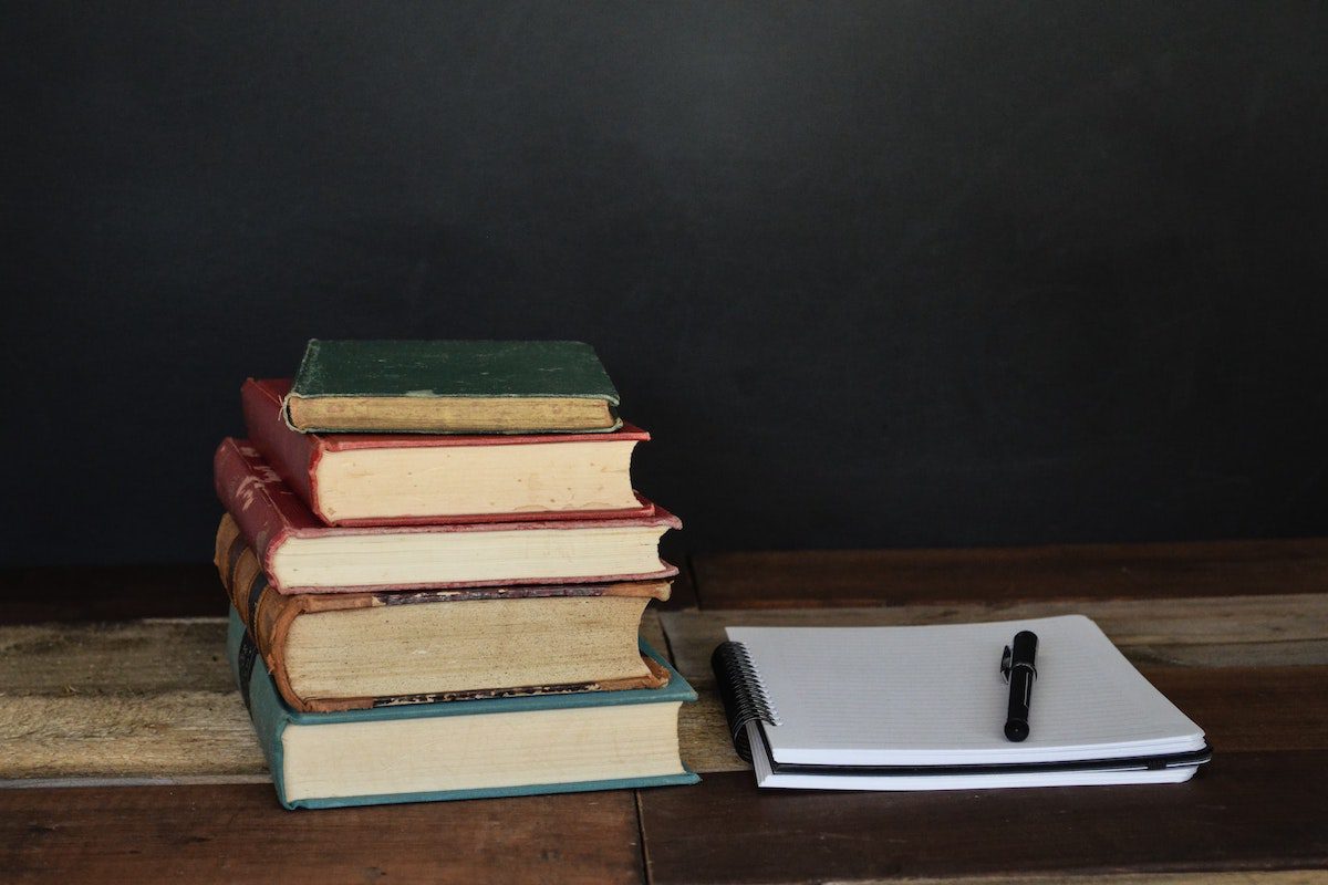 A pile of books next to a pen and notebook