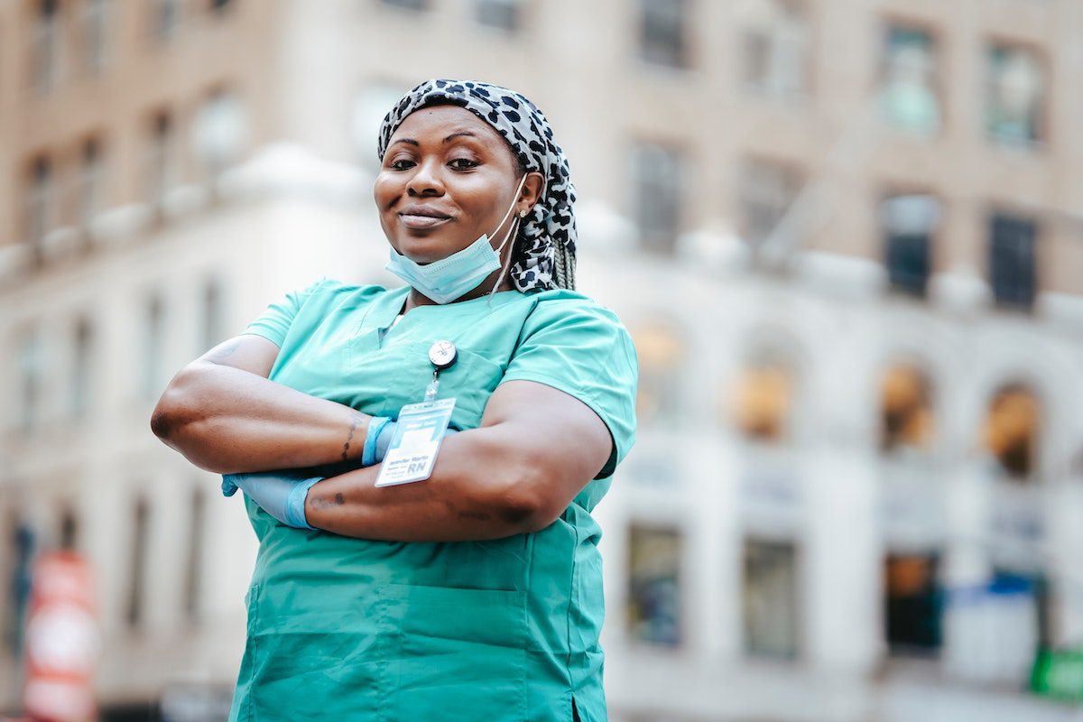 A nurse in hospital scrubs standing outside and smiling.
