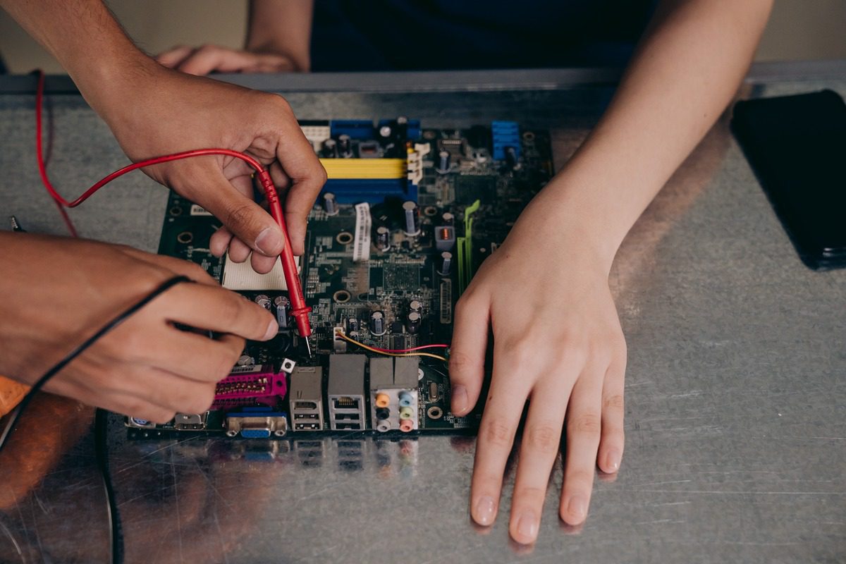 Two people working together on a circuit board.