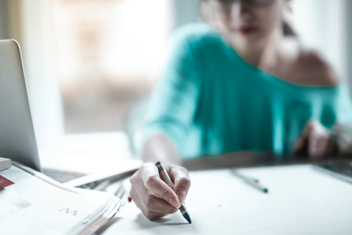 A UX designer drawing on a large sheet of paper in front of her computer