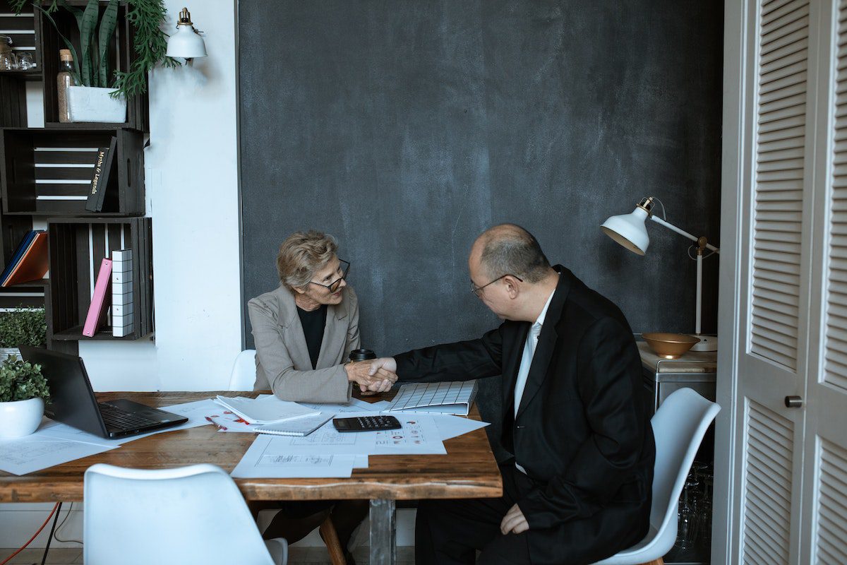 A woman and man in business suits shaking each other's hands.